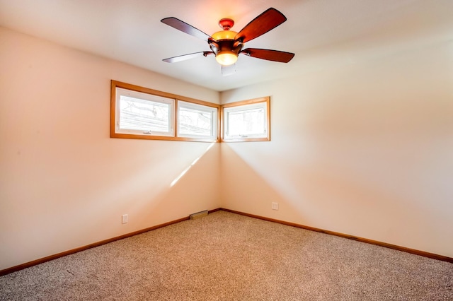 spare room featuring ceiling fan, baseboards, and light carpet