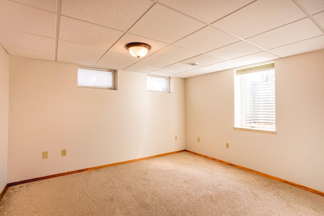 below grade area with a drop ceiling, baseboards, and carpet floors