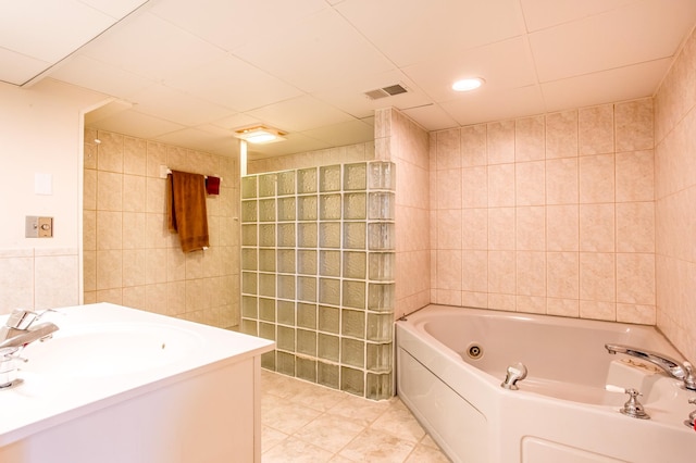 bathroom with tile patterned floors, visible vents, tile walls, a tub with jets, and walk in shower