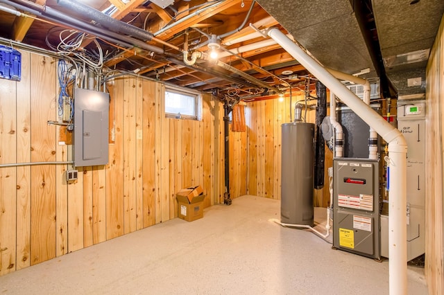 basement featuring electric panel, heating unit, gas water heater, and wood walls