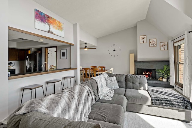 living room with lofted ceiling, a brick fireplace, and ceiling fan