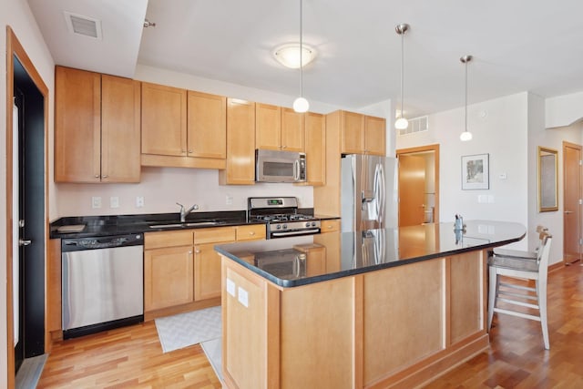 kitchen with a kitchen island with sink, stainless steel appliances, a sink, and visible vents