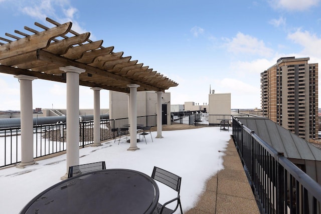 snow covered patio featuring a pergola and outdoor dining space