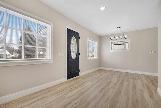 foyer entrance with light hardwood / wood-style flooring and an inviting chandelier