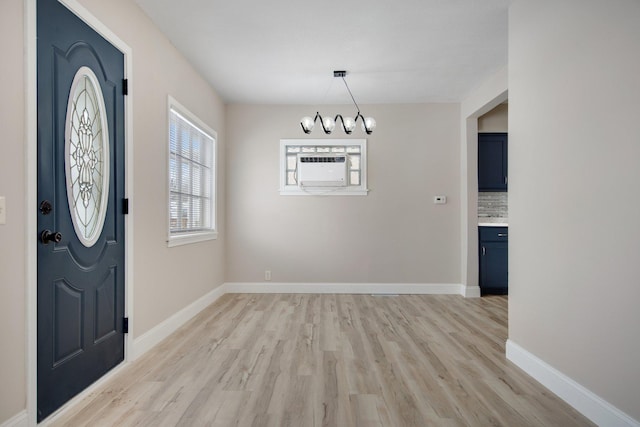 entrance foyer with a wall unit AC, a chandelier, and light wood-type flooring