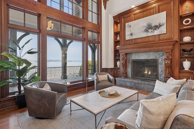 living area with built in shelves, a fireplace, and wood finished floors