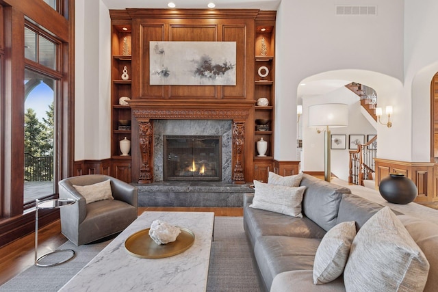 living area featuring built in features, visible vents, stairway, a high end fireplace, and wood finished floors