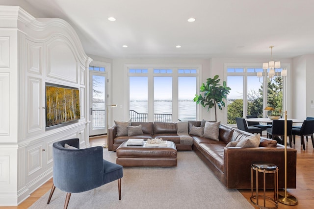 living room with light wood-type flooring, a water view, plenty of natural light, and recessed lighting