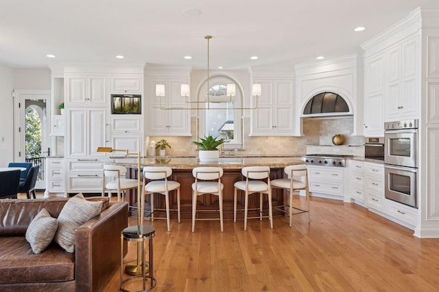 kitchen featuring a breakfast bar area, stainless steel appliances, white cabinetry, a center island, and light wood finished floors