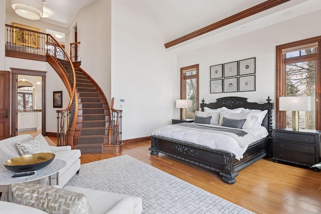 bedroom with a towering ceiling, baseboards, and wood finished floors