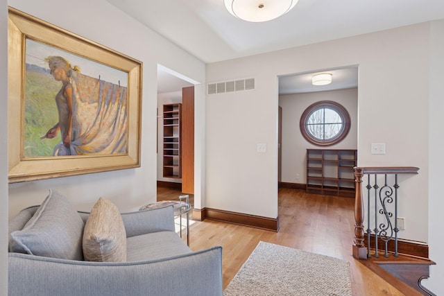 living area with wood finished floors, visible vents, and baseboards