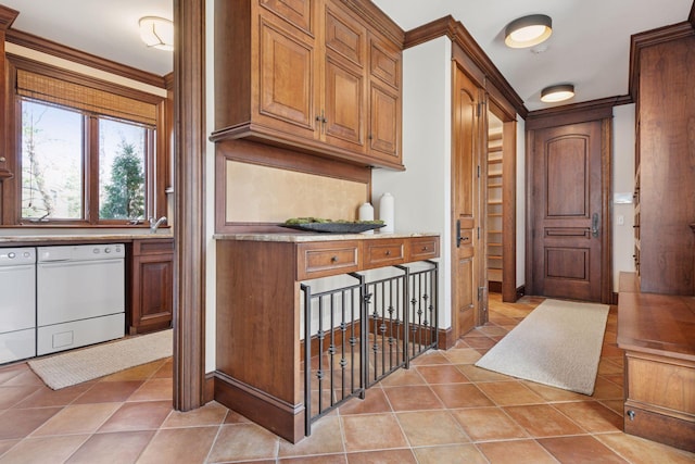 kitchen with dishwasher, light countertops, light tile patterned floors, and brown cabinetry