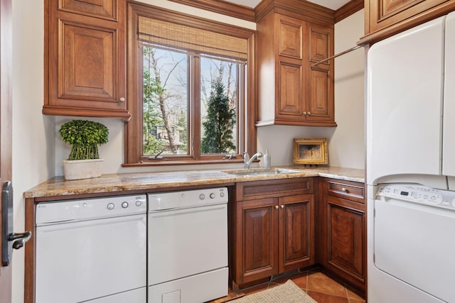 kitchen with light tile patterned floors, white appliances, a sink, light stone countertops, and brown cabinetry