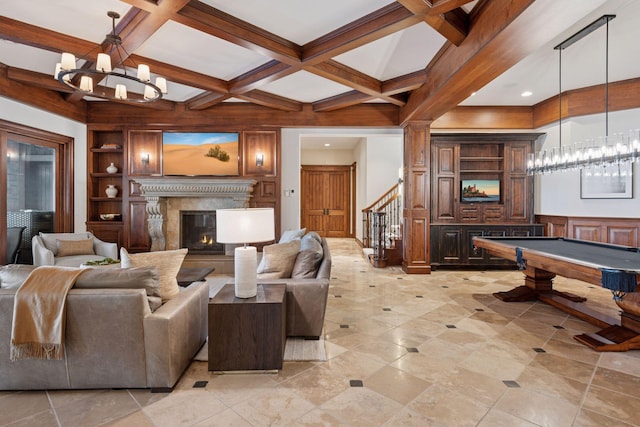 living room with beam ceiling, coffered ceiling, a notable chandelier, and a premium fireplace