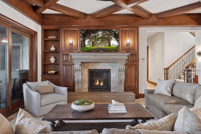 living area featuring built in shelves, coffered ceiling, beamed ceiling, and a premium fireplace