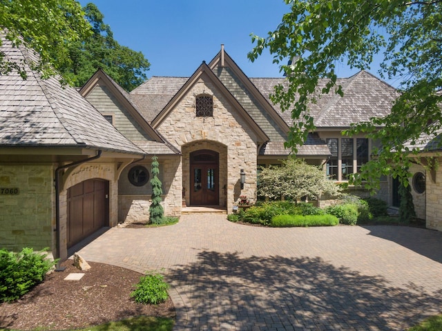 view of front of property featuring a garage, decorative driveway, and stone siding