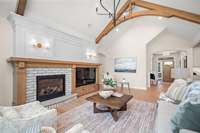 116 Spring Farm Rd, North Oaks, MN 55127 - living area with arched walkways, light wood-style flooring, beamed ceiling, a brick fireplace, and high vaulted ceiling