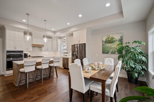 dining room with baseboards, a tray ceiling, dark wood-style flooring, and recessed lighting