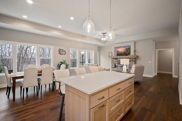 kitchen featuring a breakfast bar area, open floor plan, dark wood-type flooring, a center island, and light brown cabinetry