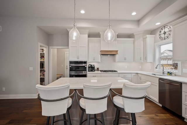 kitchen with light stone counters, dark wood finished floors, appliances with stainless steel finishes, white cabinetry, and a kitchen island