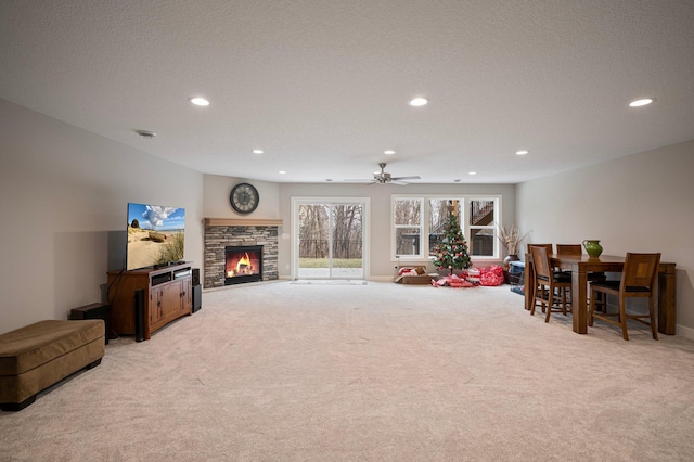 living room with recessed lighting, light carpet, ceiling fan, a stone fireplace, and a textured ceiling