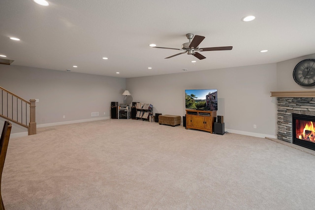 living room featuring recessed lighting, stairway, light colored carpet, and a stone fireplace