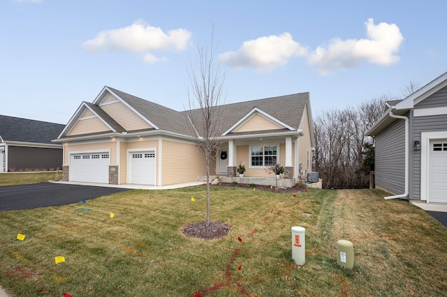 view of front of house featuring aphalt driveway, a front lawn, a garage, and roof with shingles