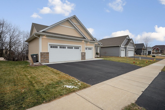 craftsman inspired home featuring aphalt driveway, stone siding, an attached garage, and a front lawn