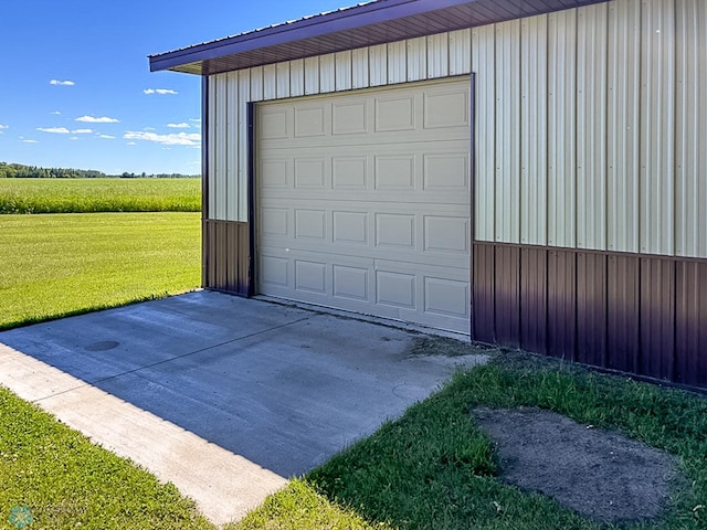 garage featuring concrete driveway and a rural view