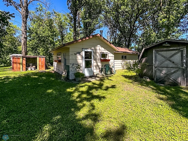 rear view of house featuring a yard, an outdoor structure, and a storage shed