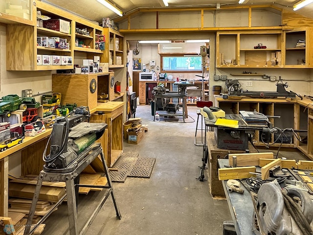 interior space featuring unfinished concrete flooring, vaulted ceiling, and a workshop area