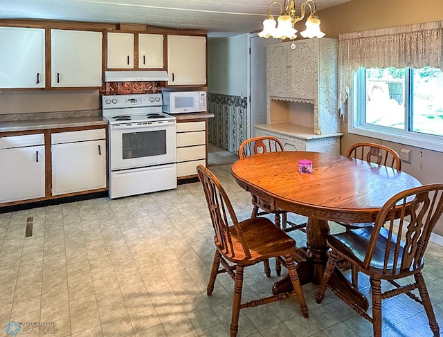 kitchen featuring hanging light fixtures, white appliances, white cabinets, and under cabinet range hood