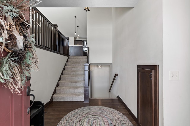 stairway with a high ceiling, wood finished floors, and baseboards