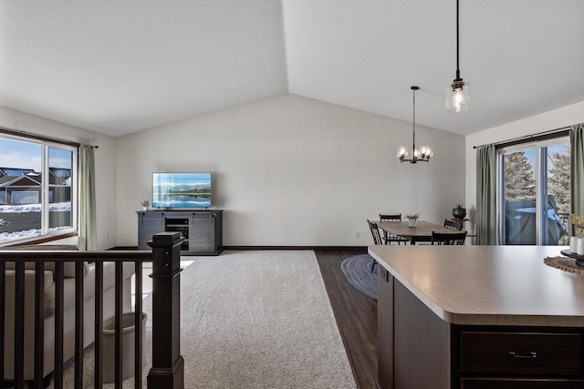 interior space featuring a wealth of natural light, dark wood-style floors, a chandelier, and vaulted ceiling