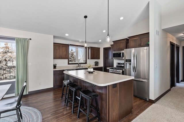 kitchen with visible vents, a kitchen island, stainless steel appliances, light countertops, and dark brown cabinets