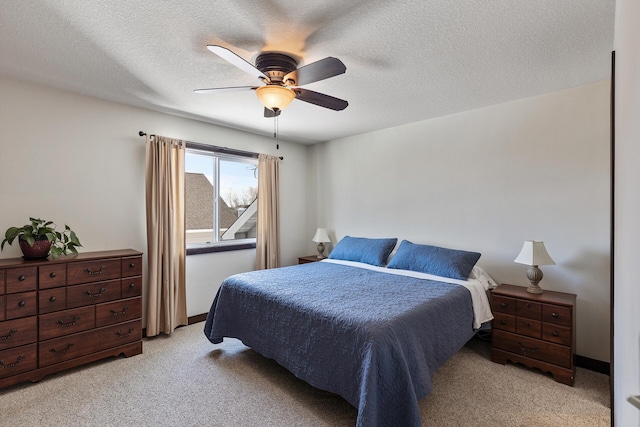 bedroom featuring a ceiling fan, light colored carpet, baseboards, and a textured ceiling