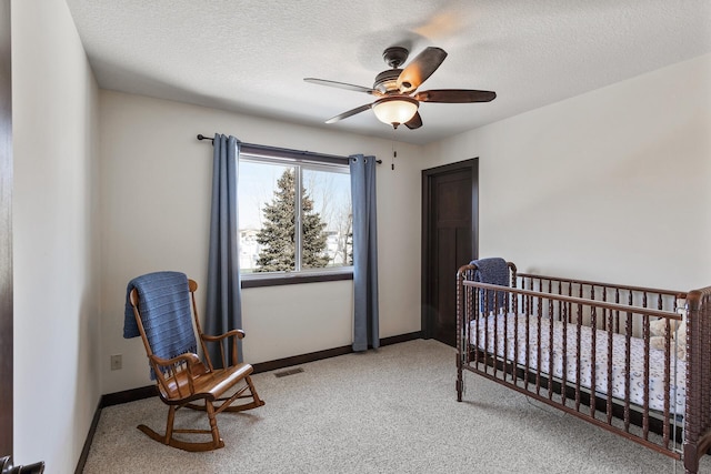 carpeted bedroom featuring visible vents, a textured ceiling, baseboards, and a nursery area