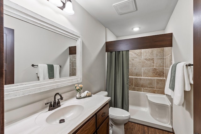 bathroom with visible vents, toilet, a shower with shower curtain, wood finished floors, and vanity