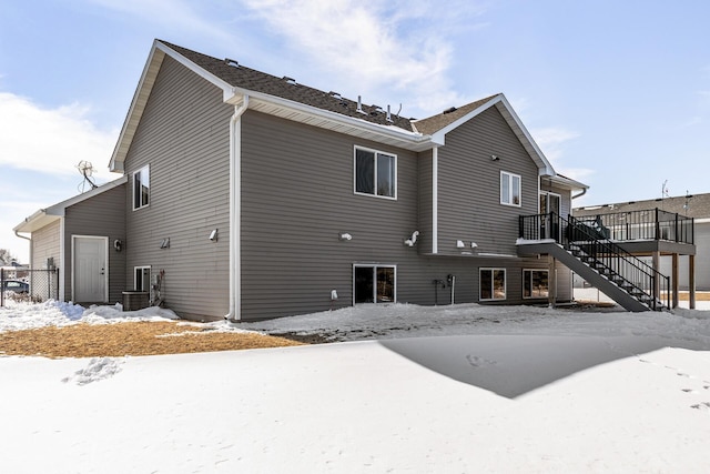 snow covered house with stairs and a deck