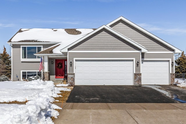 view of front of home featuring aphalt driveway, stone siding, and a garage