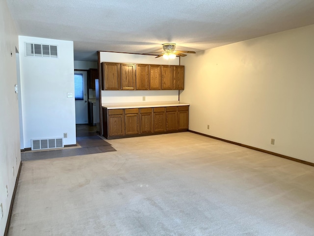 unfurnished living room featuring ceiling fan, light carpet, and a textured ceiling