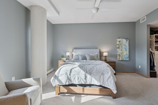 bedroom with a walk in closet, a baseboard radiator, light colored carpet, visible vents, and baseboards