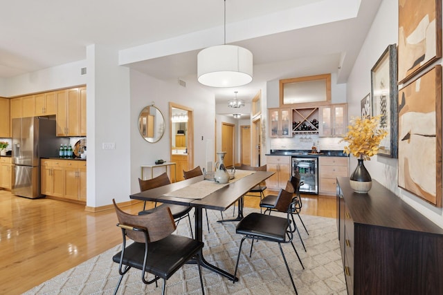 dining area featuring a dry bar, light wood-style flooring, wine cooler, and visible vents