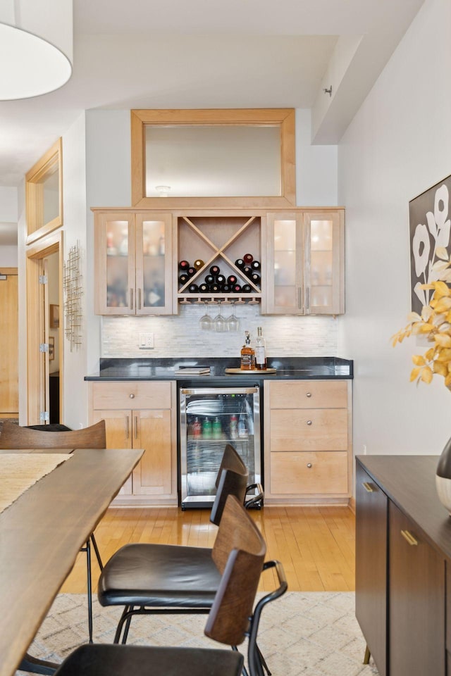 bar featuring a dry bar, light wood-style floors, wine cooler, and backsplash