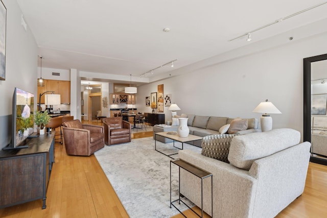 living area featuring visible vents, rail lighting, and light wood-style flooring