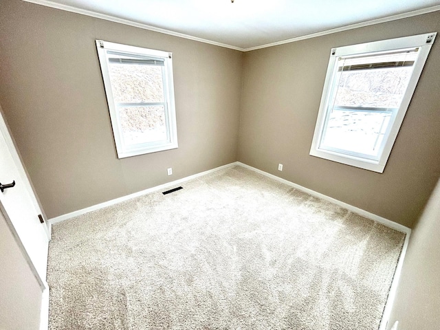 carpeted empty room with ornamental molding, a wealth of natural light, visible vents, and baseboards