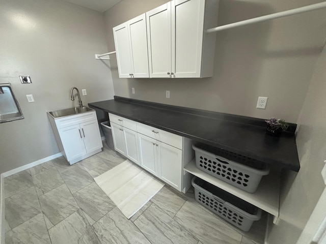 clothes washing area featuring marble finish floor, cabinet space, baseboards, and a sink