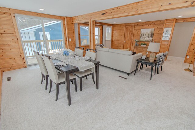 dining area featuring recessed lighting, light colored carpet, and wood walls