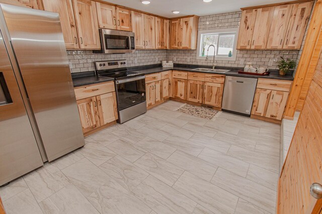 kitchen featuring stainless steel appliances, dark countertops, recessed lighting, backsplash, and a sink