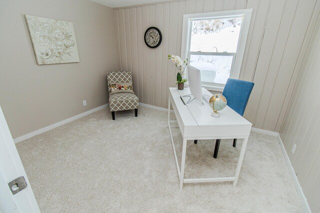 office space featuring light carpet, wood walls, and baseboards